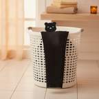 Black jeans, clean and pet-hair free, draped over a white laundry basket with a bear-shaped pet hair remover on top in a mode