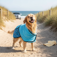Golden Retriever wearing a grey super absorbent pet bathrobe, shaking off water after a beach swim, on a sandy path near a ca